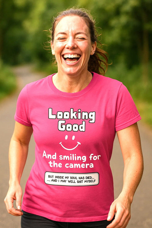Pink women's t-shirt. Text on front: Looking good (smiley face icon) and smiling for the camera. Text underneath in box (but inside my soul has died and I may well shit myself).